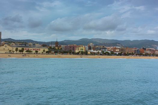 Barcelona beach in winter, with a calm sea and a cloudy blue sky