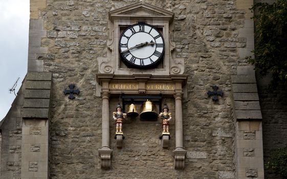 Close-up of a clock in a stone wall in Carfax Tower, Oxford with two automaton and brass bells