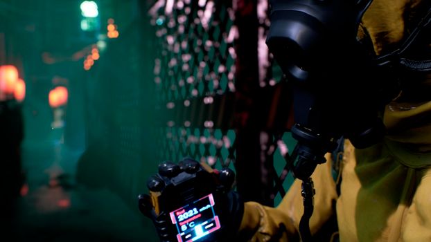 A nuclear physicist sits on a neon street and checks the surrounding radiation with a dosimeter. Post-apocalyptic world concept. View of an deserted apocalyptic street.