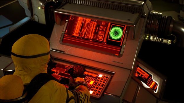 A medic in protective chemical clothing is working at a computer. A man in a yellow bacteriological protective suit and gas mask.