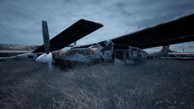 Rusty and broken planes stand in a field against a hazy blue sky. A lot of destroyed, destroyed, abandoned planes.