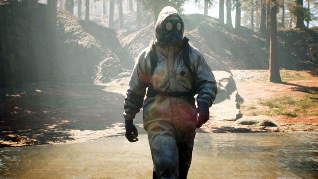 A Stalker in military protective clothing and a gas mask walks through a summer sunny forest. The concept of a post-apocalyptic world after a nuclear war.