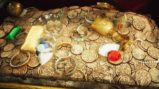 Pirate treasures in a dark cave. Old coins, diamonds, and gold treasures. A lot of jewelry made of gold statuettes, precious stones, bracelets and chests.