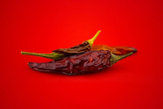 Dried chili peppers on red background. Macro image