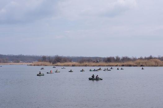 Mass fishing on the Domotkan River, Ukraine. A large number of fishermen with fishing rods on boats catch fish.