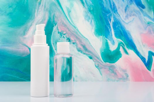 Face cream and lotion on white table against blue marbled background with copy space. Concept of natural skin care products for fresh, young looking skin