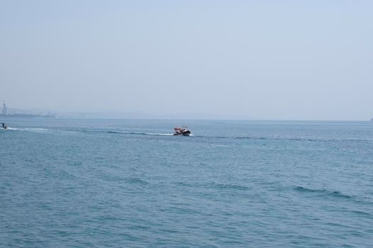 Aerial shot of the open sea on a cloudy day. Blue sky, ships in the distance and boundless horizon.