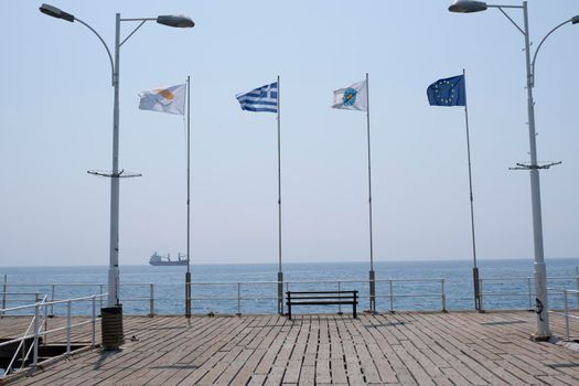 Various flags fluttering in the wind in the morning on the pier in the ancient Greek city of Limassol.