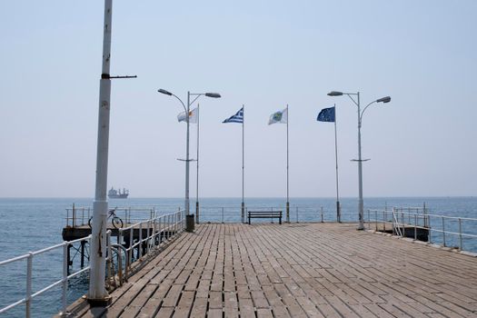 Various flags fluttering in the wind in the morning on the pier in the ancient Greek city of Limassol.
