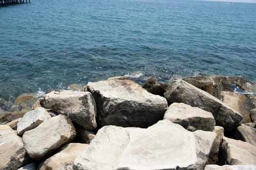 Close-up of a stone beach on a clear day. Rocks and pebbles on the beach, flooded with sea spray and waves.