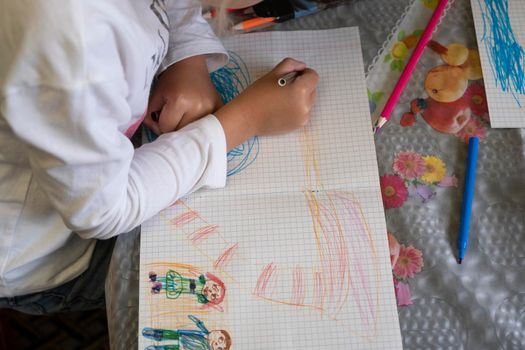 Happy child draws fairy-tale character with felt-tip pens on paper.
