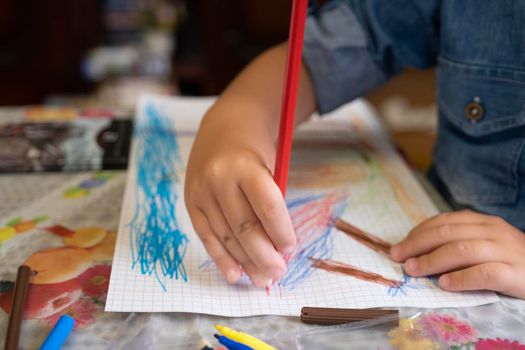 Happy child draws fairy-tale character with felt-tip pens on paper.