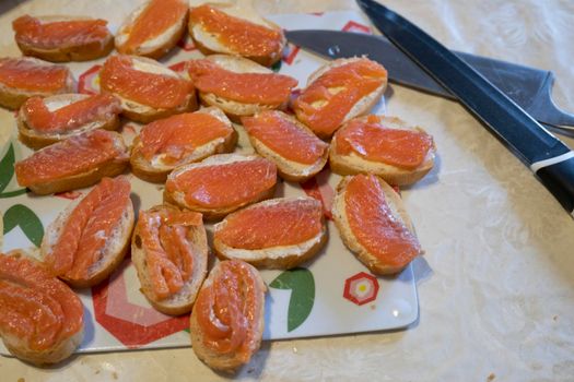 A woman lays out sandwiches with the fish on the plate. Cooking, fish dishes, healthy and diet food.