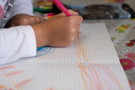 Happy child draws fairy-tale character with felt-tip pens on paper.