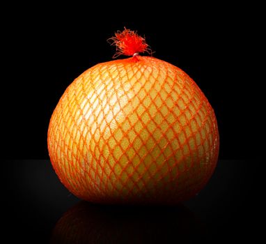 Pomelo citrus fruit in a shipping orange package close up isolated on a black background