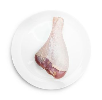 One RAW turkey leg on a white plate isolated on a white bacground. With clipping path