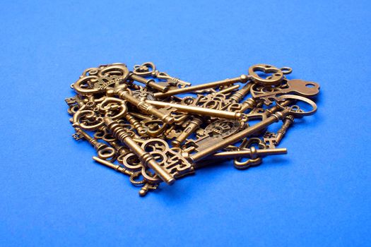 Old, vintage keys in the shape of a heart isolated on blue bacground