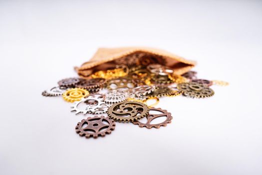 A pile of gear wheels and cogs in different colors poured out of a burlap bag. Future, gear, wheel, metal. Industrial concept. Selective focus.