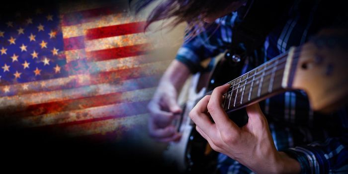 Electric guitar man playing on US flag background. Closeup Photography.