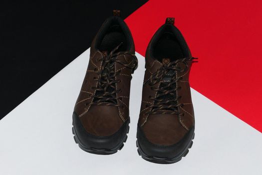 Stylish men's sneakers or leather brown shoes on a colored background.