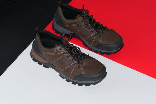 Stylish men's sneakers or leather brown shoes on a colored background.