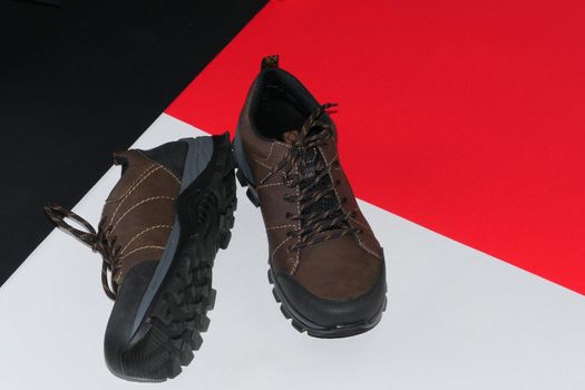 Stylish men's sneakers or leather brown shoes on a colored background.