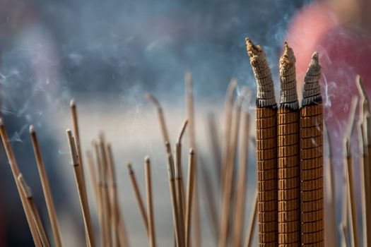 Incense burning with white smoke in an incense pot. There is a lot of smoke. Selective focus.