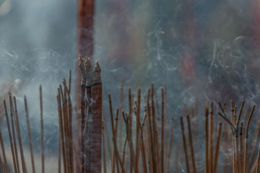 Incense burning with white smoke in an incense pot. There is a lot of smoke. Selective focus.