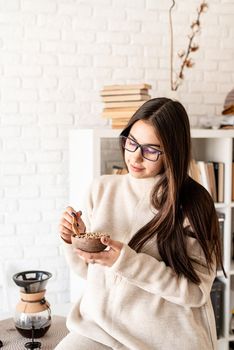 Alternative coffee brewing. Young brunette woman brewing coffee in chemex, smelling green coffee beans