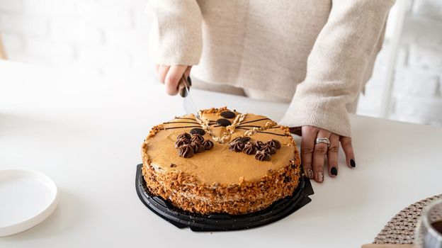 close up of woman hands cutting a brown cake