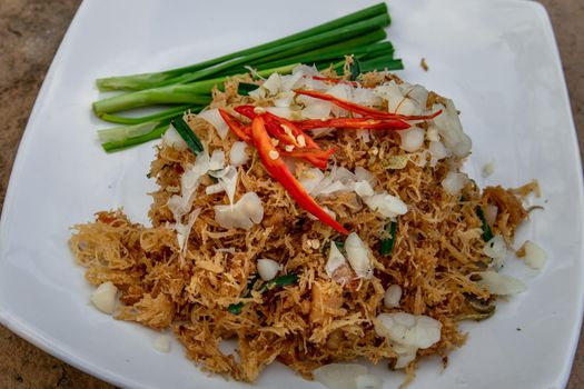 Asian eating food, Mee Grob is an sweet and sour crispy noodles, made from Thai rice noodle with sweet and sour sauce on white plate, Sweet & Sour Crispy Rice Noodles, Oblique view from the top.