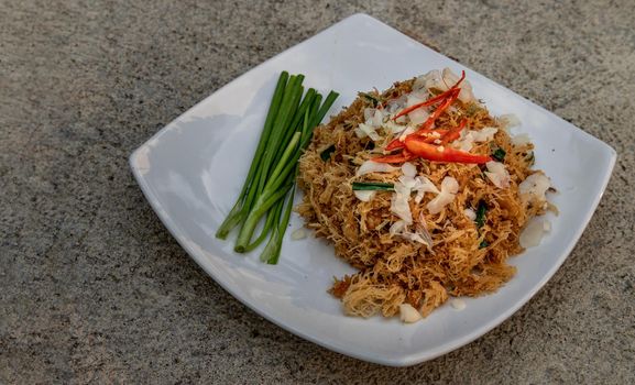 Asian eating food, Mee Grob is an sweet and sour crispy noodles, made from Thai rice noodle with sweet and sour sauce on white plate, Sweet & Sour Crispy Rice Noodles, Oblique view from the top.