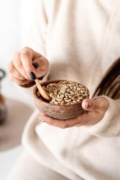Alternative coffee brewing. Woman hand holding bowl with green coffee beans