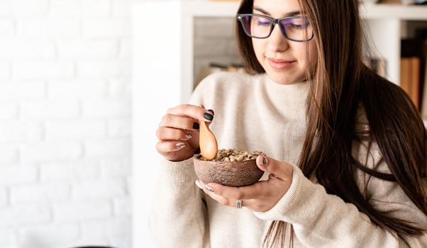 Alternative coffee brewing. Young brunette woman brewing coffee in chemex, smelling green coffee beans