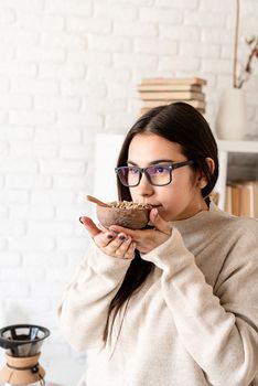 Alternative coffee brewing. Young brunette woman brewing coffee in chemex, smelling green coffee beans