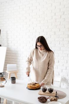 Alternative coffee brewing. Young woman brewing coffee in chemex and cutting a cake
