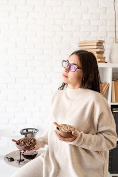 Alternative coffee brewing. Young brunette woman brewing coffee in chemex, smelling green coffee beans