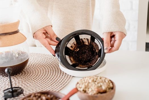 Alternative coffee brewing. Young woman brewing coffee in chemex standing at the white table with various stuff for alternative coffee brewing