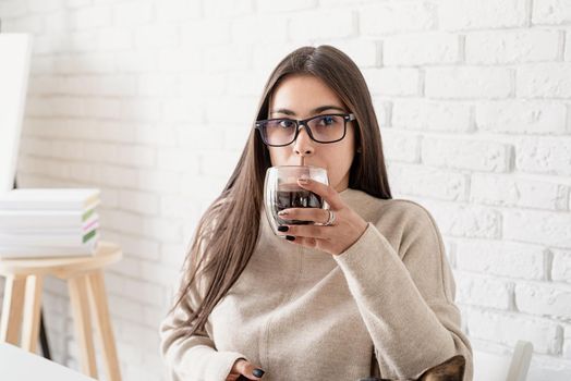 Alternative coffee brewing. Young brunette woman drinking hot black coffee sitting at the white table