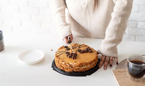 close up of woman hands cutting a brown cake