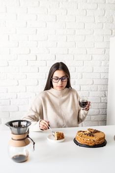 Alternative coffee brewing. Young brunette woman drinking hot black coffee sitting at the white table
