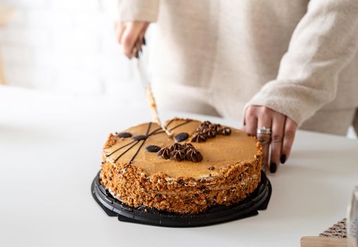 close up of woman hands cutting a brown cake