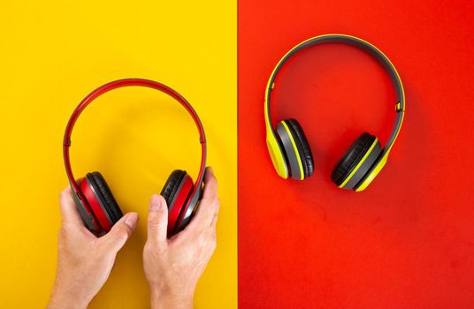 hand holding a headphones on red and yellow background. Music concept.