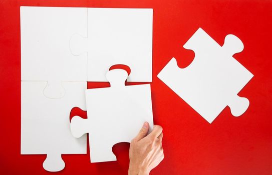 Concept of business,hand solving a puzzle piece on red background.