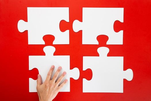 Concept of business,hand solving a puzzle piece on red background.