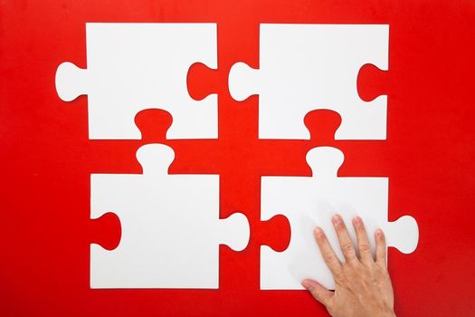 Concept of business,hand solving a puzzle piece on red background.