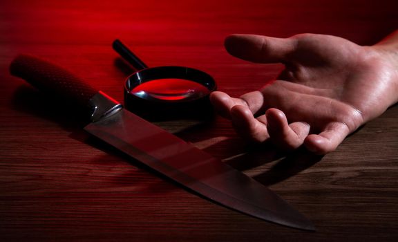 Hand of a man and big knife on floor, Crime Investigation conceptual image