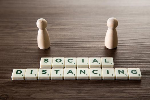 Conceptual image about social distancing, mandatory due to the coronavirus outbreak, covid-19. Pair of wooden human figures standing with distancing