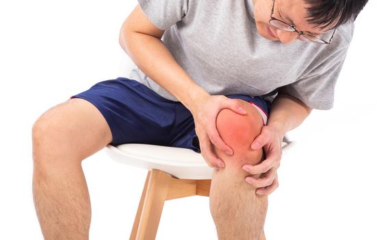 Sore pain of knee. Sprain and arthritis symptoms. middle age man holding his hurt knee over white background.
