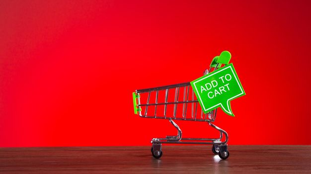 Tiny shopping cart with the word ADD TO CART in speech bubble. Add to cart shopping conceptual.